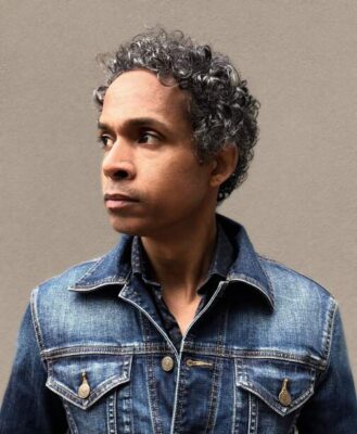 portrait of David Chariandy. Author shows profile of face with short curly hair, wearing a jean jacket.