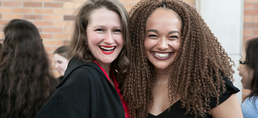 Two Massey College students hug and smile for the camera
