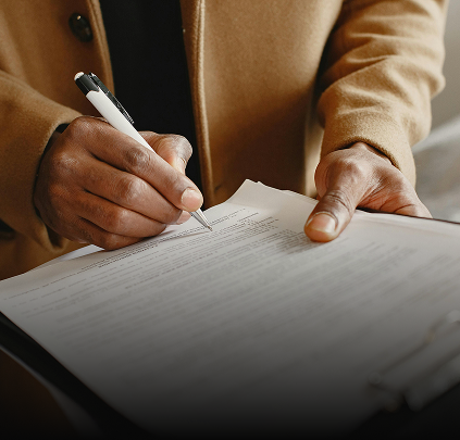 Close up of a persons hand signing a form