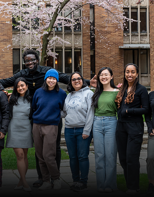 Students at Massey College stand smiling together on campus
