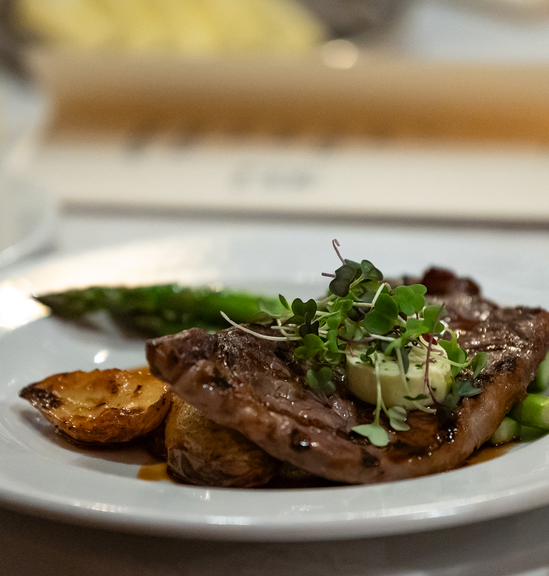 Steak frites garnished with herbed butter and microgreens